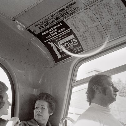 Old black-and-white photo of people seated on a bus, two women chatting, a man looking straight ahead.
