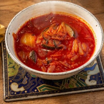 Bowl of spicy red chill soup on a table.