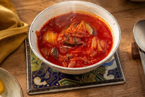 Bowl of spicy red chill soup on a table.
