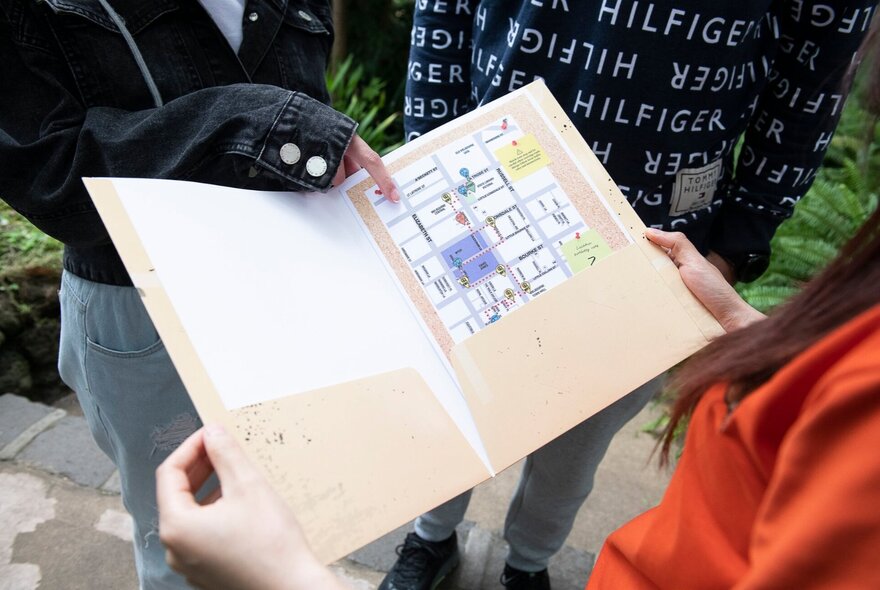 Participants with casebook paperwork looking for clues in the pages.