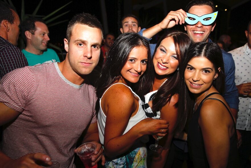 A group of people posing for a photograph in a nightclub.