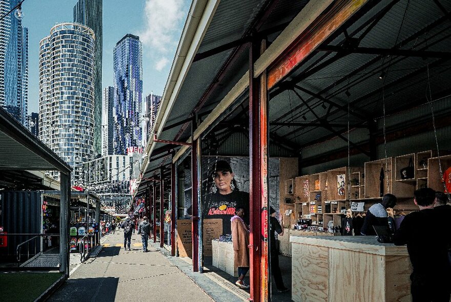 View down outdoor market lane, with cityscape at rear.