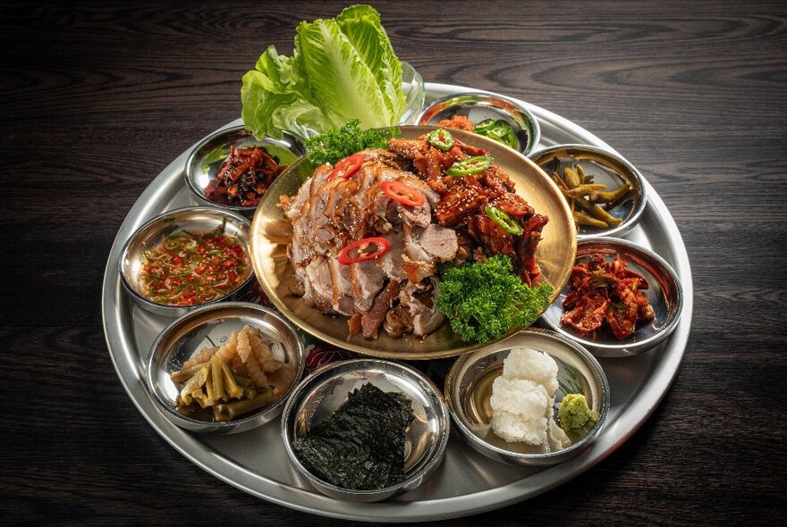 A central bowl of food, surrounded by smaller bowls of garnishes and condiments.