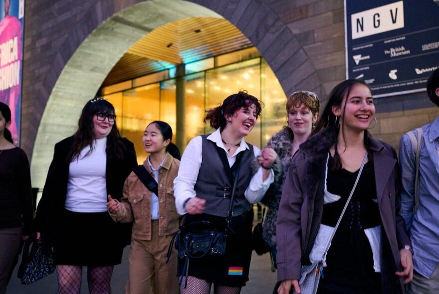 A group of young people looking happy and walking away from the entrance of NGV. 