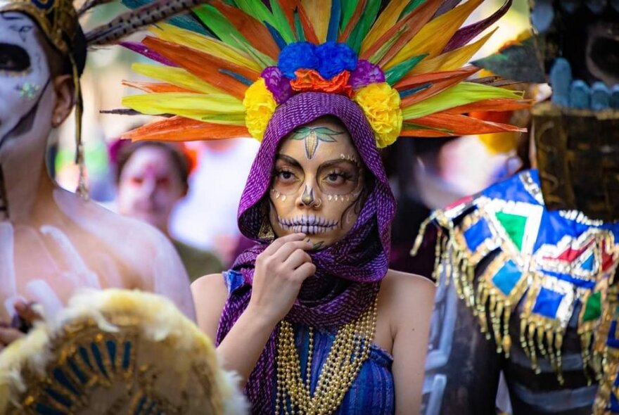 People dressed in Day of the Dead costumes and face make-up in a crowd.