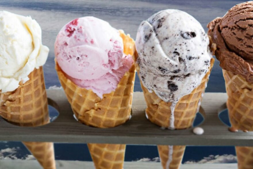 Ice cream cones lined up in a row with vanilla, strawberry and chocolate flavours.