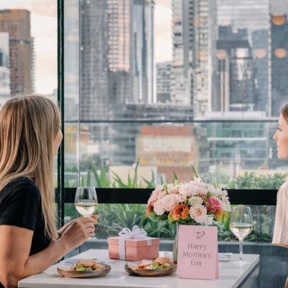 Two individuals enjoying a meal together in a stylish, window-side restaurant setting. 