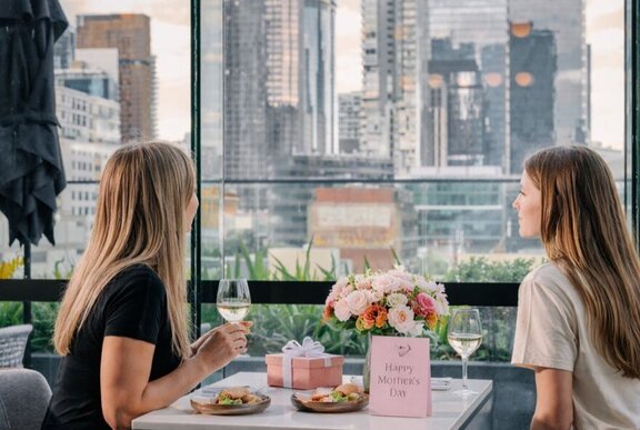 Two individuals enjoying a meal together in a stylish, window-side restaurant setting. 