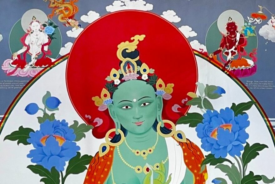 Buddhist Tara image of green figure with red mandala and blue flowers.