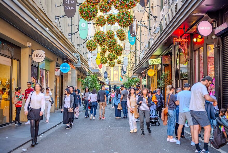 A busy laneway with Christmas decorations hanging above.