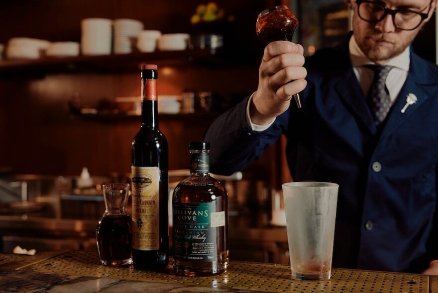 Bar tender making whisky cocktails at a bar.