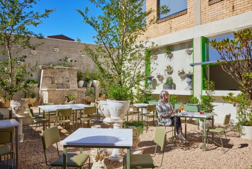 An outdoor eating area with tables, chairs and plants. 