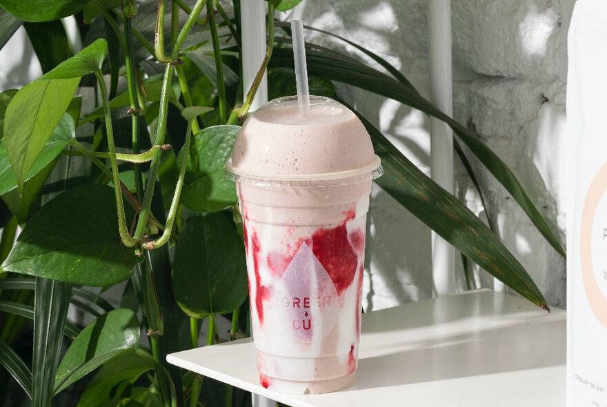 Green Cup smoothie on a white outside table.