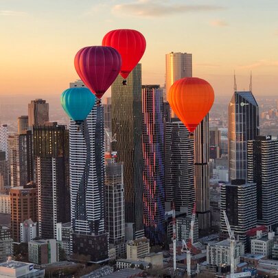 Hot air balloons flying over the city.