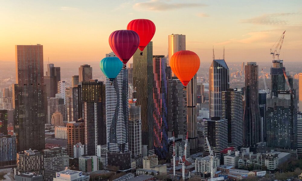 Hot air balloons flying over the city.