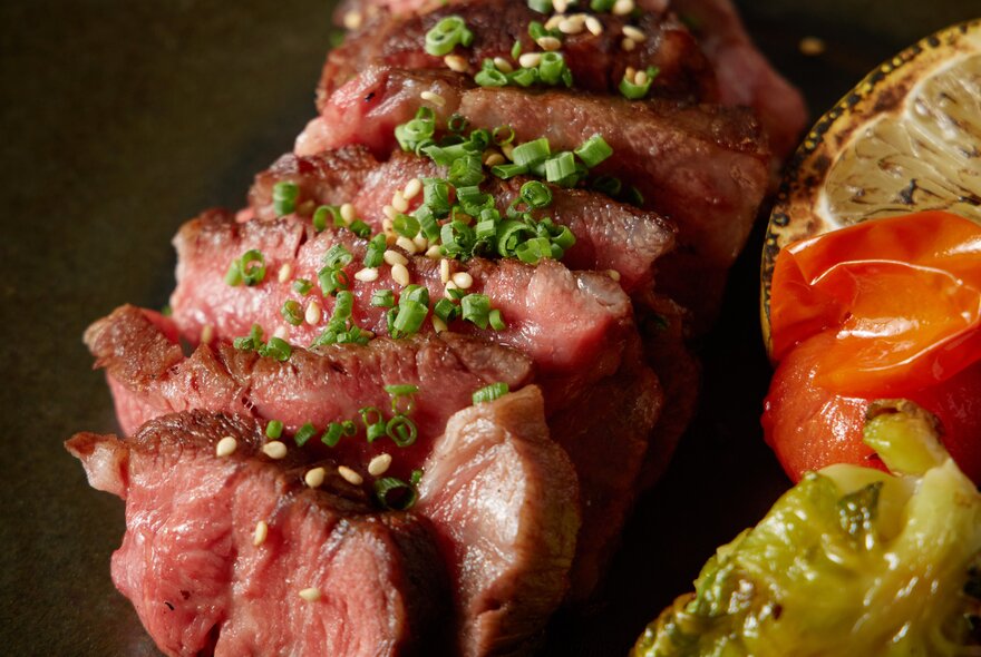 Thinly cut steak with garnish and a side of vegetables.