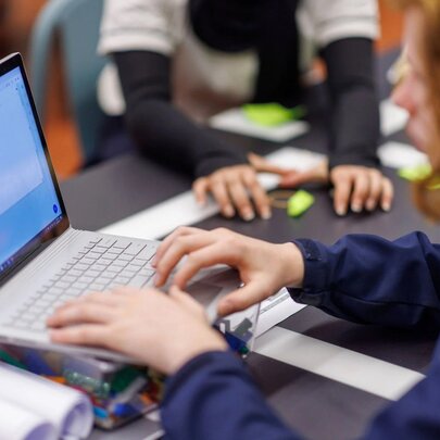 Side view of a child typing on a laptop.