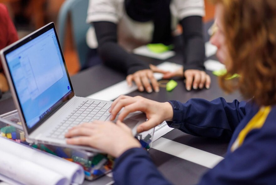 Side view of a child typing on a laptop.
