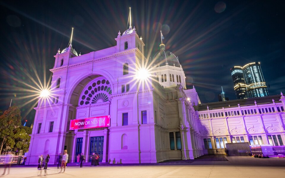 The Royal Exhibition Building lit up at night in purple lights. 