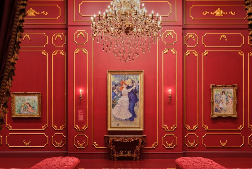 A Renoir painting of a couple dancing in a red gallery with a grand chandelier.