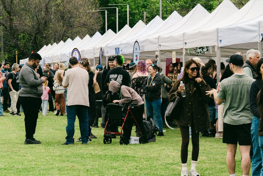 A long row of market stalls at an outdoor event, people milling around in front of them.