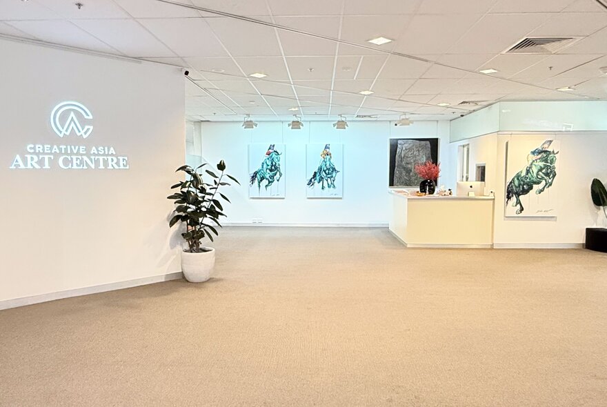 Gallery space with a potted plant and large artworks on display.