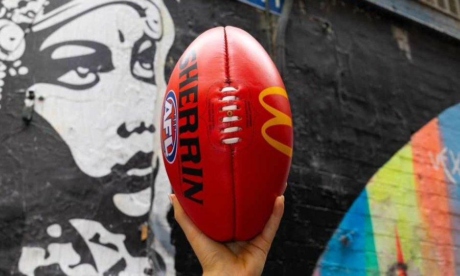 A person holding a football in their hand against a wall