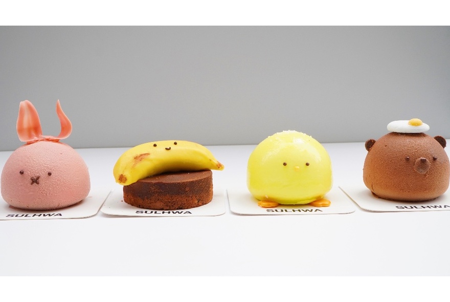 A row of Asian desserts in the shape of little animal and fruit heads. 