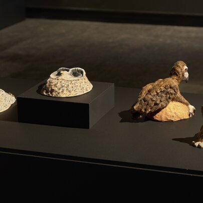 A collection of four small sculptural artworks displayed on a black surface.