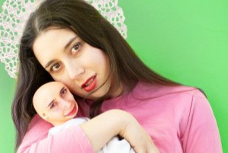 Woman cuddling a strange bald doll.