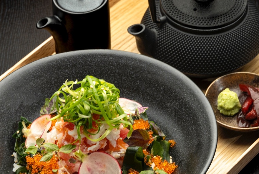 A Japanese-style salad with salmon roe, radishes and sliced green vegetables as a garnish.