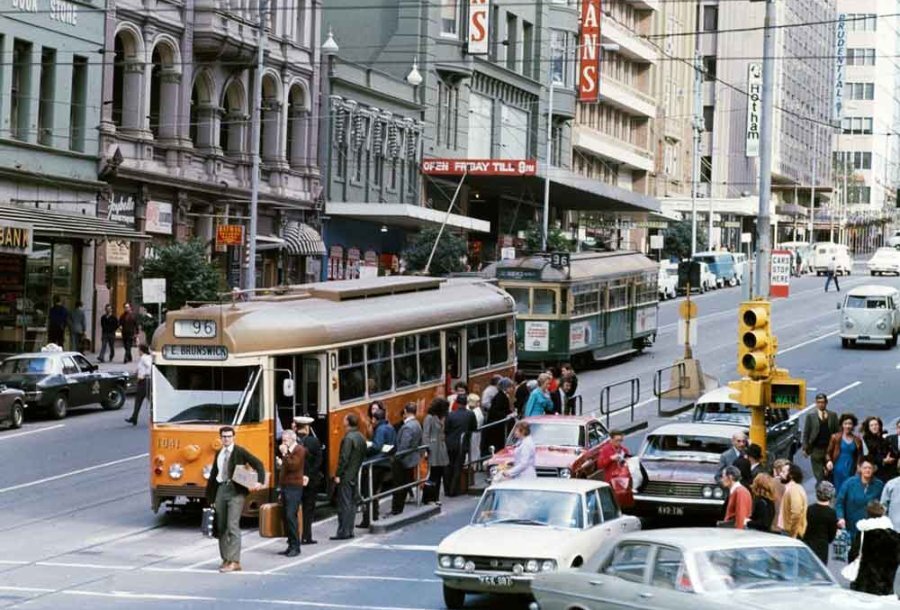 An old photo of a yellow tram on a city street.