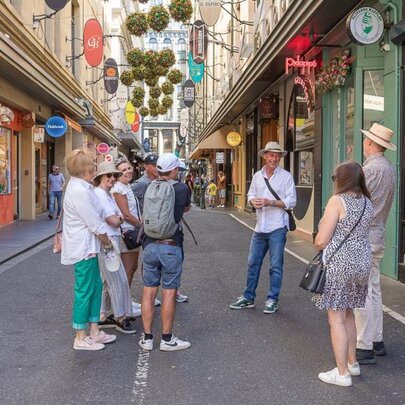 Small tour group standing in a Melbourne laneway, listening to a man speaking.