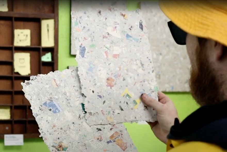 A person holding up two sheets of handmade paper.