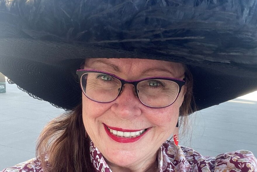 Walking tour guide Deb Robinson, a smiling middle-aged woman wearing glasses and a large black sun hat.