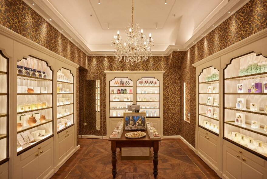 A beautiful small store with bottles on shelves and a chandelier.