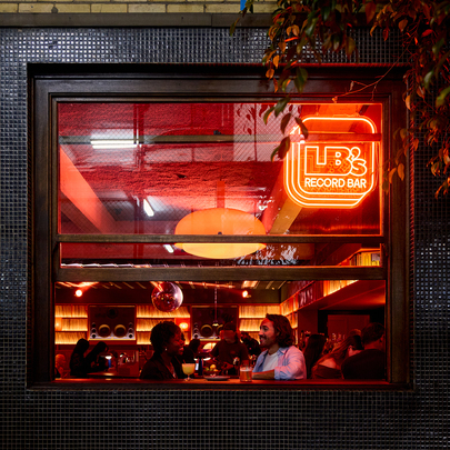 A couple having drinks inside the window of a cosy bar.
