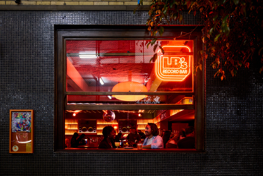 A couple having drinks inside the window of a cosy bar.