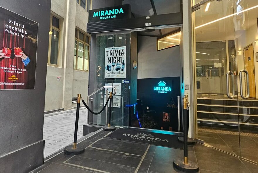 Venue entryway with signage, glass doors, steps and cordon ropes.
