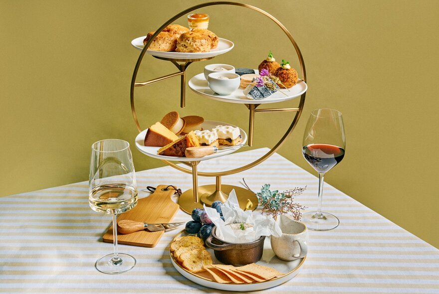A gold high tea tray with wine and cheese.