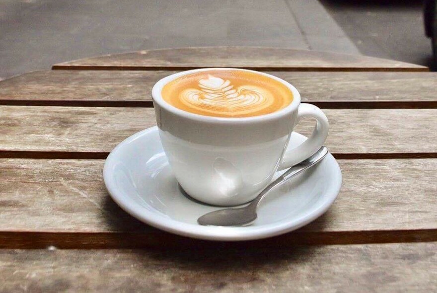 A full coffee cup sitting on an outdoor table.