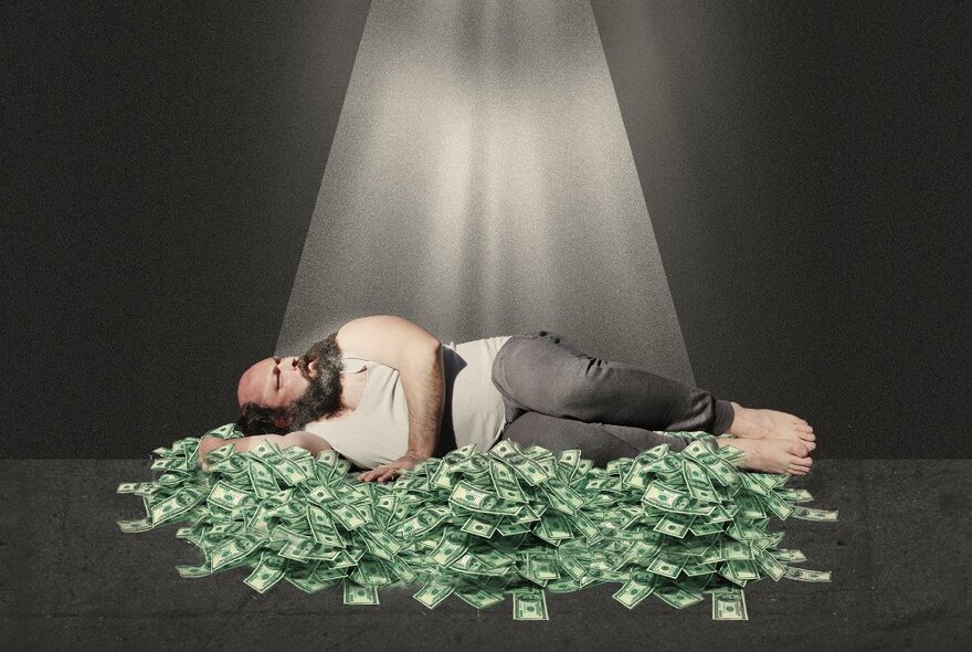 A man sleeping on a bed of green dollar bills with a laser beam shining down on him. 