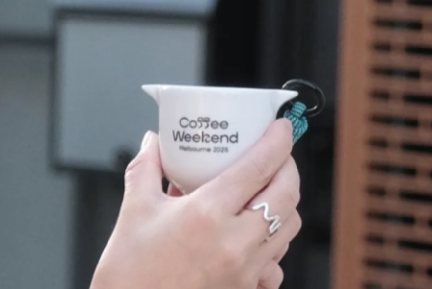 A hand holding a cup that has the words Coffee Weekend printed on the side.