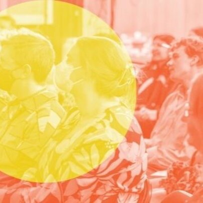 A seated and attentive audience listening to a talk;  there is large yellow circle superimposed over the orange coloured image.
