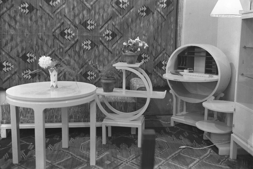 A black and white image of circular tables and shelving. 