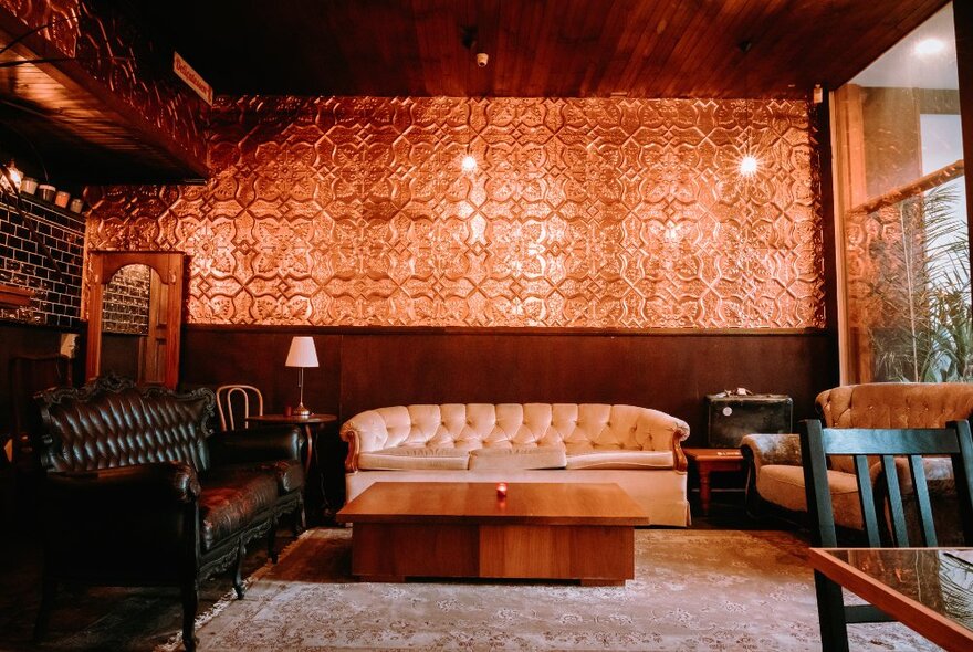 A bar setting with warm brown tones and Chesterfield sofas. 