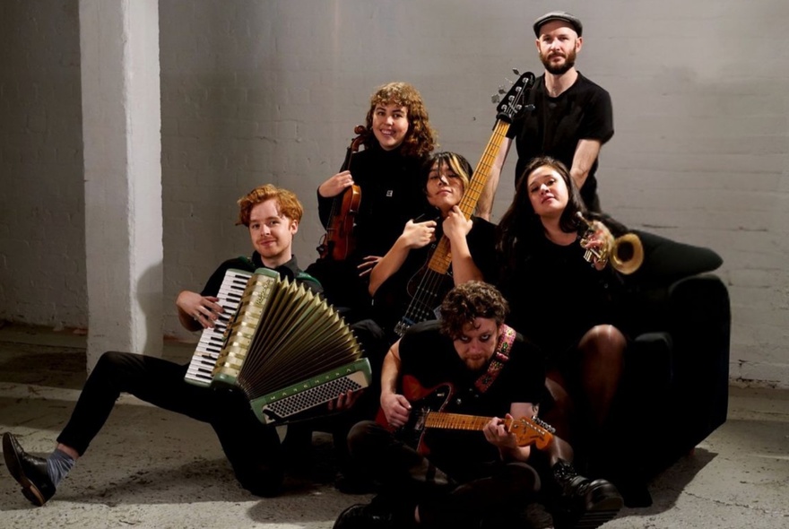 A group of musicians in black, each playing their instruments.