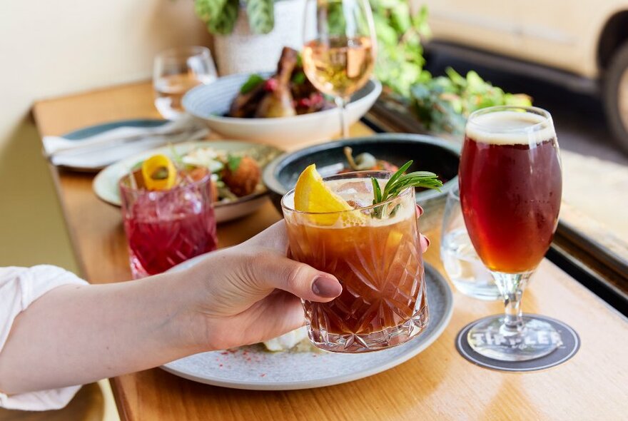 A restaurant bench set with dishes, wines and cocktails.