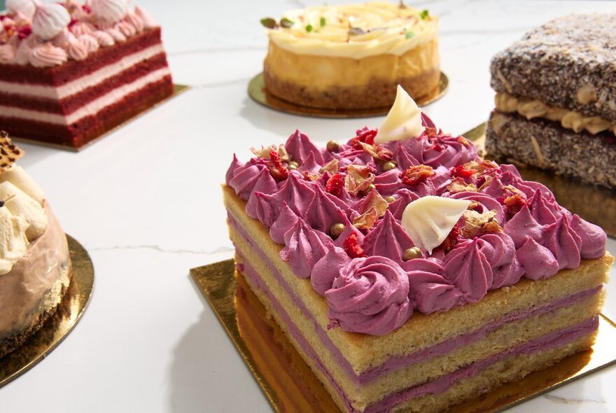 A selection of iced and decorated cakes on a white table top.