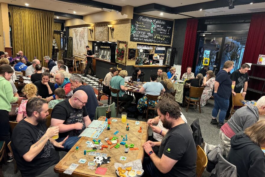 A room inside a pub filled with people seated at tables and playing board games.